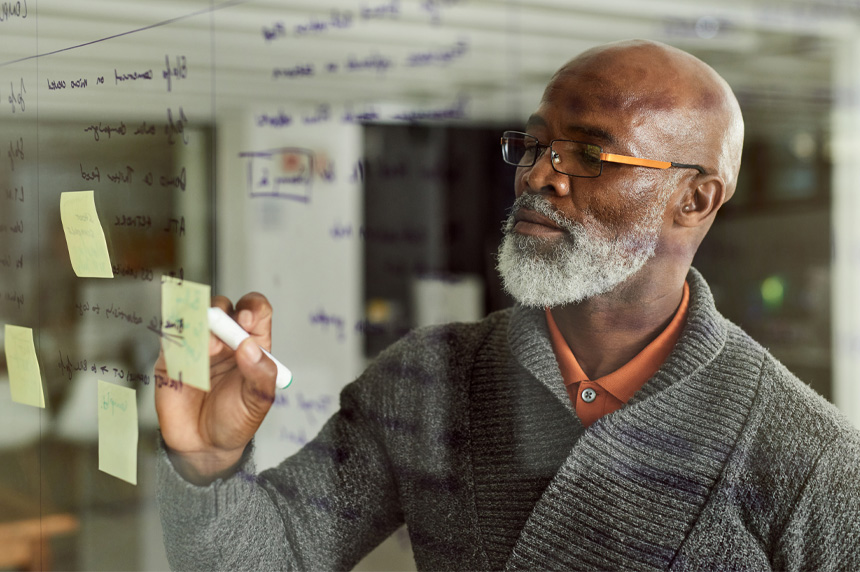 man writing notes on glass window